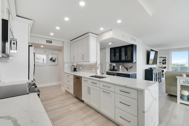 123 Lakeshore Dr Unit 1145, North Palm Beach, FL 33408 - kitchen with stainless steel appliances, a sink, backsplash, white cabinets, and light stone counters