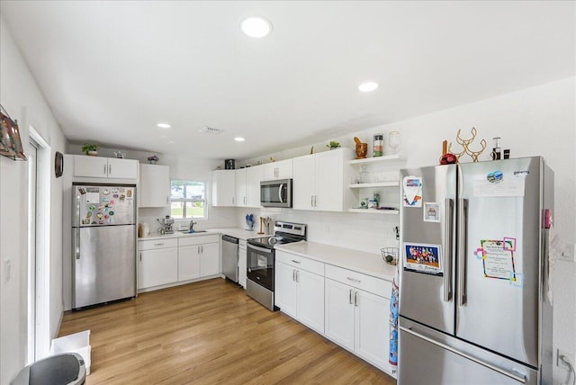 300 SW Prima Vista Blvd, Port Saint Lucie, FL 34983 - kitchen with appliances with stainless steel finishes, a sink, light countertops, white cabinetry, and light wood finished floors