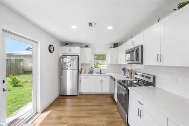 300 SW Prima Vista Blvd, Port Saint Lucie, FL 34983 - kitchen with appliances with stainless steel finishes, a sink, backsplash, white cabinets, and light countertops