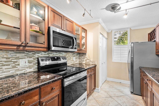 3606 S Ocean Blvd Unit 201, Highland Beach, FL 33487 - kitchen featuring stainless steel appliances, rail lighting, ornamental molding, backsplash, and brown cabinets