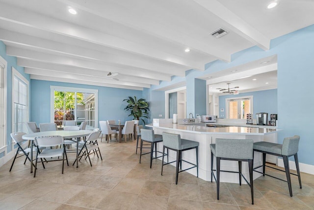3606 S Ocean Blvd Unit 201, Highland Beach, FL 33487 - kitchen with beamed ceiling, a kitchen bar, a peninsula, light countertops, and a sink