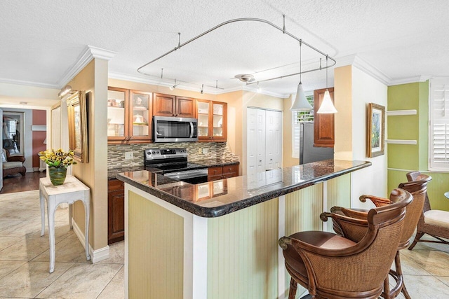 3606 S Ocean Blvd Unit 201, Highland Beach, FL 33487 - kitchen featuring stainless steel appliances, ornamental molding, backsplash, brown cabinets, and glass insert cabinets