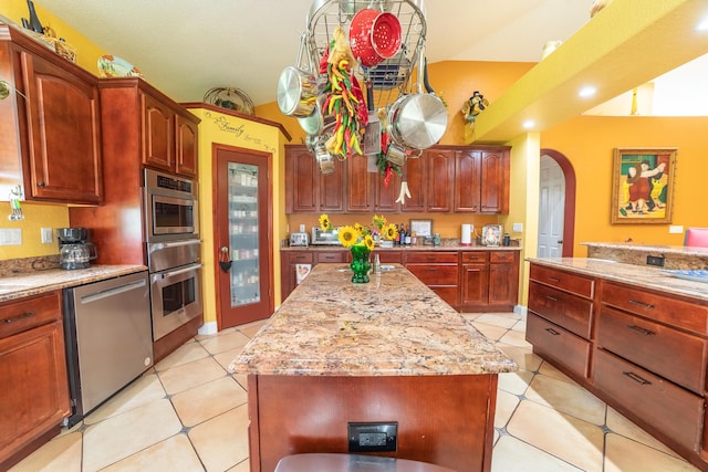 7611 SW 21st Pkwy, Okeechobee, FL 34974 - kitchen featuring stainless steel dishwasher, arched walkways, a warming drawer, light stone counters, and light tile patterned floors