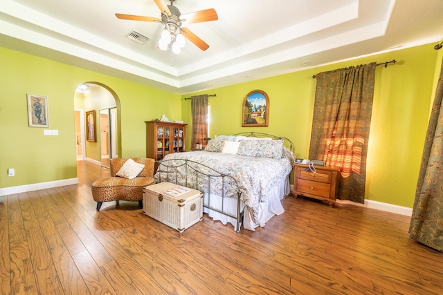 7611 SW 21st Pkwy, Okeechobee, FL 34974 - bedroom featuring a tray ceiling, arched walkways, wood finished floors, and baseboards