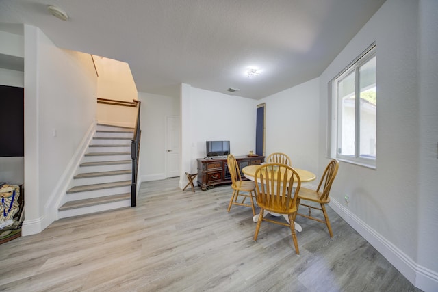 2364 Center Stone Ln, Riviera Beach, FL 33404 - dining area featuring stairway, light wood finished floors, baseboards, and a textured ceiling