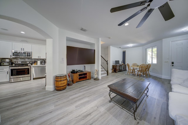 2364 Center Stone Ln, Riviera Beach, FL 33404 - living area featuring ceiling fan, light wood finished floors, stairway, baseboards, and arched walkways