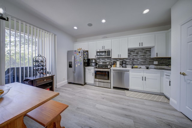 2364 Center Stone Ln, Riviera Beach, FL 33404 - kitchen featuring stainless steel appliances, decorative backsplash, white cabinetry, light wood-type flooring, and recessed lighting