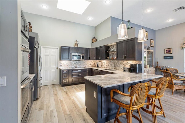 10312 Inverness Way, Port Saint Lucie, FL 34986 - kitchen featuring stainless steel appliances, a sink, a peninsula, open shelves, and light wood-style flooring