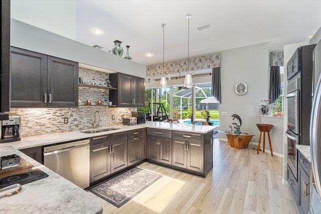 10312 Inverness Way, Port Saint Lucie, FL 34986 - kitchen featuring appliances with stainless steel finishes, a sink, decorative backsplash, light wood finished floors, and decorative light fixtures