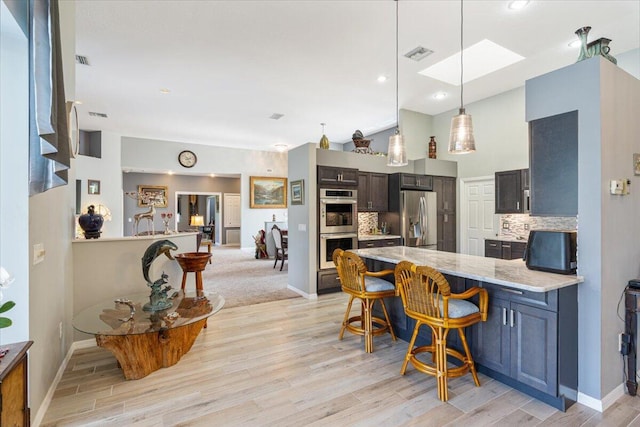 10312 Inverness Way, Port Saint Lucie, FL 34986 - kitchen featuring stainless steel appliances, a peninsula, backsplash, a kitchen bar, and light wood-style flooring