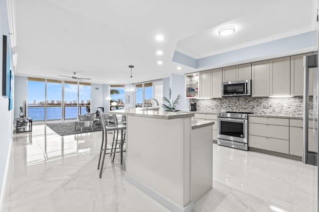 2650 Lake Shore Dr Unit 406, Riviera Beach, FL 33404 - kitchen featuring appliances with stainless steel finishes, tasteful backsplash, light marble finish flooring, crown molding, and a kitchen island with sink