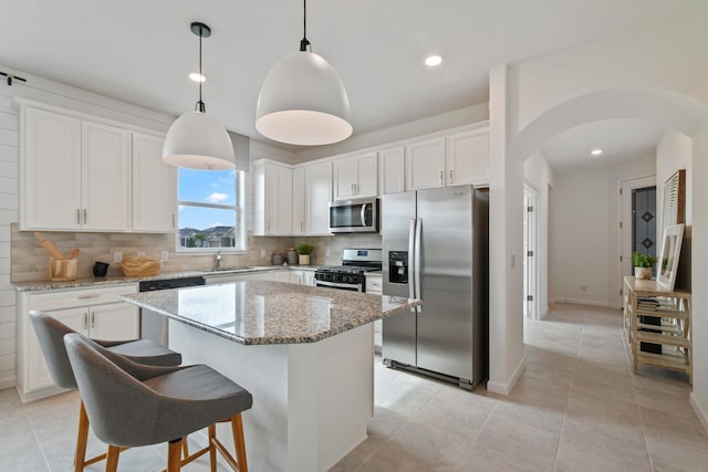 12755 SW Cattleya Ln Unit 224, Port Saint Lucie, FL 34987 - kitchen with appliances with stainless steel finishes, arched walkways, tasteful backsplash, a center island, and white cabinetry