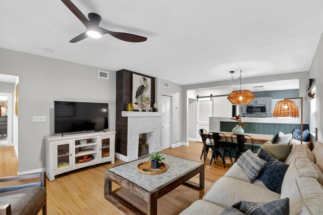404 S M St Unit 1, Lake Worth Beach, FL 33460 - living area with a barn door, ceiling fan, light wood-style floors, and a large fireplace