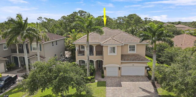 5621 SW Longspur Ln, Palm City, FL 34990 - mediterranean / spanish home featuring a tile roof, decorative driveway, a garage, stucco siding, and a balcony