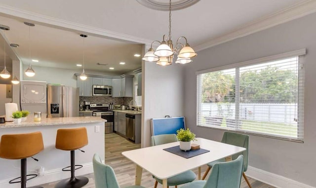 1022 State St, West Palm Beach, FL 33407 - dining area with stacked washer and clothes dryer, light wood finished floors, a chandelier, ornamental molding, and recessed lighting