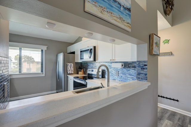 5725 Pelican Pointe Dr Unit 4, Sebastian, FL 32958 - kitchen with stainless steel appliances, decorative backsplash, white cabinetry, wood finished floors, and baseboards