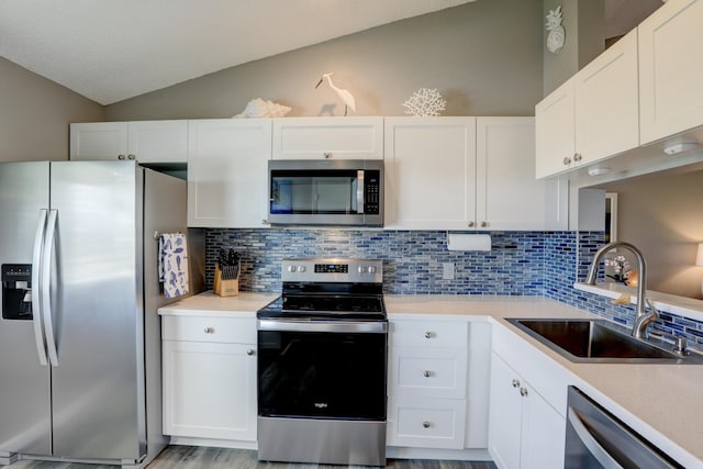 5725 Pelican Pointe Dr Unit 4, Sebastian, FL 32958 - kitchen with stainless steel appliances, a sink, vaulted ceiling, backsplash, and white cabinets