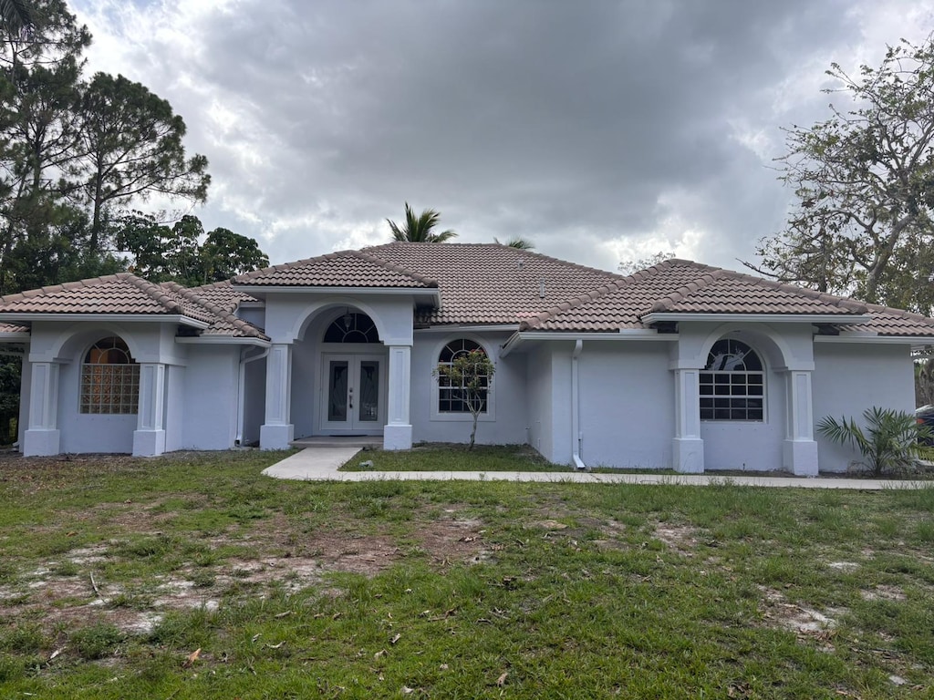 6749 Royal Palm Bch, West Palm Beach, FL 33412 - mediterranean / spanish-style house with french doors, a tile roof, a front lawn, and stucco siding