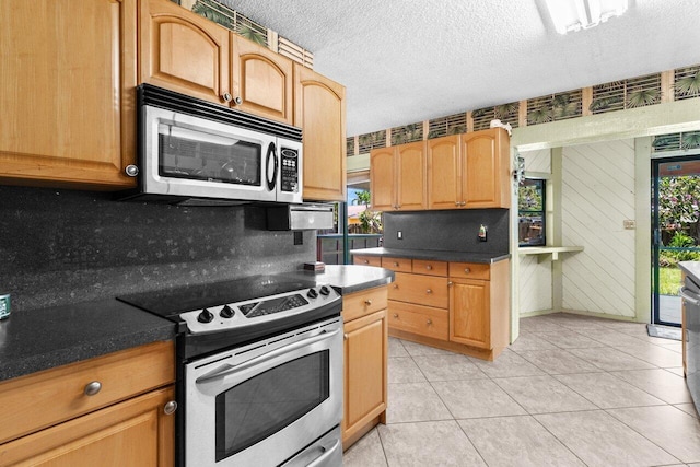 4694 Brady Blvd, Delray Beach, FL 33445 - kitchen featuring stainless steel appliances, decorative backsplash, dark countertops, a textured ceiling, and light tile patterned flooring