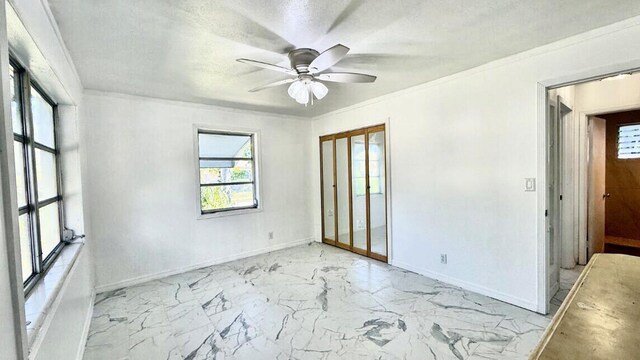 802 Lytle St, West Palm Beach, FL 33405 - empty room featuring baseboards, a ceiling fan, light marble finish flooring, crown molding, and a textured ceiling