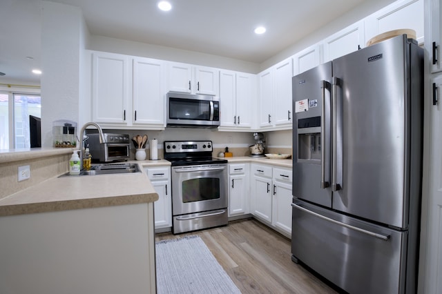 1020 E Longport Cir Unit A1, Delray Beach, FL 33444 - kitchen with stainless steel appliances, a sink, light wood-type flooring, light countertops, and white cabinetry