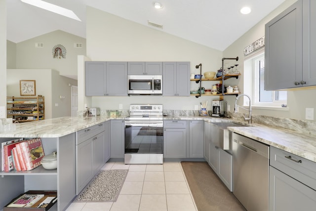 4393 SE Scotland Cay Way, Stuart, FL 34997 - kitchen with appliances with stainless steel finishes, open shelves, gray cabinets, a peninsula, and high vaulted ceiling