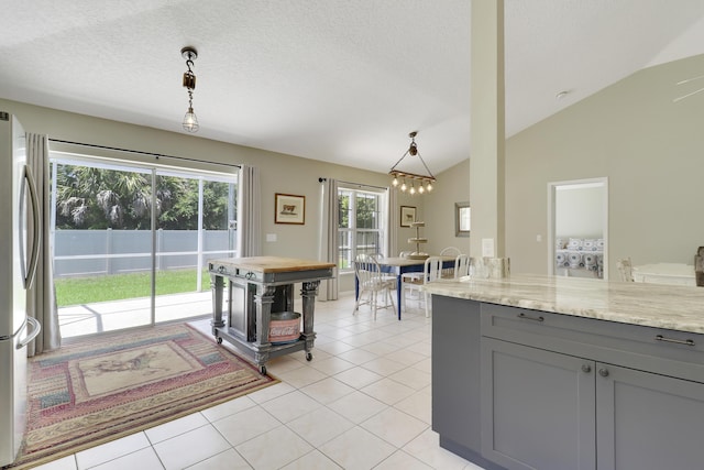 4393 SE Scotland Cay Way, Stuart, FL 34997 - kitchen with gray cabinets, freestanding refrigerator, light tile patterned flooring, light stone counters, and vaulted ceiling