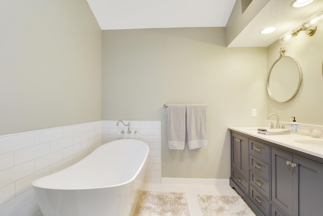 4393 SE Scotland Cay Way, Stuart, FL 34997 - bathroom with tile walls, double vanity, a freestanding tub, wainscoting, and tile patterned floors