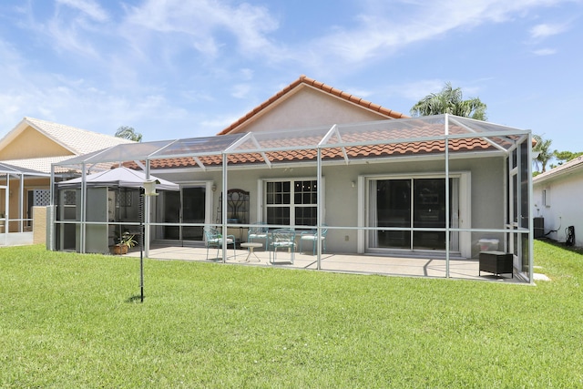 4393 SE Scotland Cay Way, Stuart, FL 34997 - rear view of house with a tile roof, a patio, stucco siding, glass enclosure, and a yard