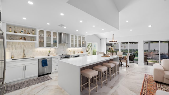21415 Campo Allegro Dr, Boca Raton, FL 33433 - kitchen featuring appliances with stainless steel finishes, wall chimney exhaust hood, a sink, light marble finish floors, and a breakfast bar area