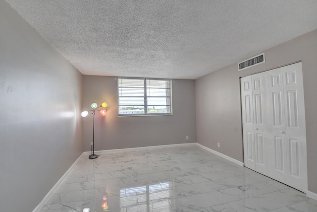 5500 NW 2nd Ave Three, Unit Three, Boca Raton, FL 33487 - unfurnished bedroom featuring baseboards, light marble finish floors, a textured ceiling, and a closet