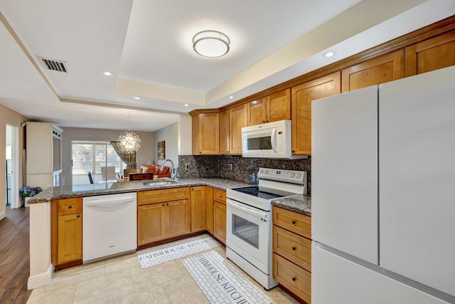 2901 NW 46th Ave Unit 101, Lauderdale Lakes, FL 33313 - kitchen featuring white appliances, a tray ceiling, a chandelier, a peninsula, and tasteful backsplash