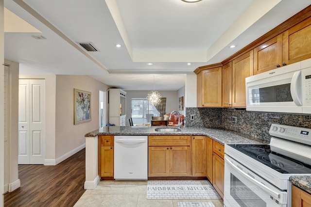 2901 NW 46th Ave Unit 101, Lauderdale Lakes, FL 33313 - kitchen with white appliances, a raised ceiling, a peninsula, dark stone counters, and recessed lighting