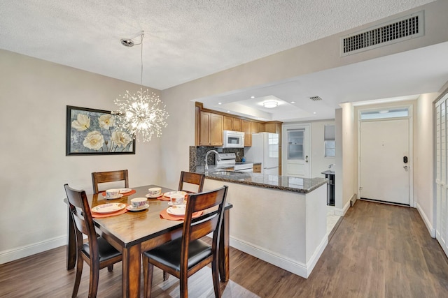 2901 NW 46th Ave Unit 101, Lauderdale Lakes, FL 33313 - dining room featuring wood finished floors, a chandelier, a textured ceiling, and a tray ceiling