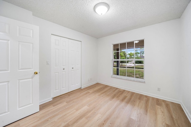17832 43rd Rd N, Loxahatchee, FL 33470 - unfurnished bedroom featuring light wood-type flooring, a textured ceiling, a closet, and baseboards