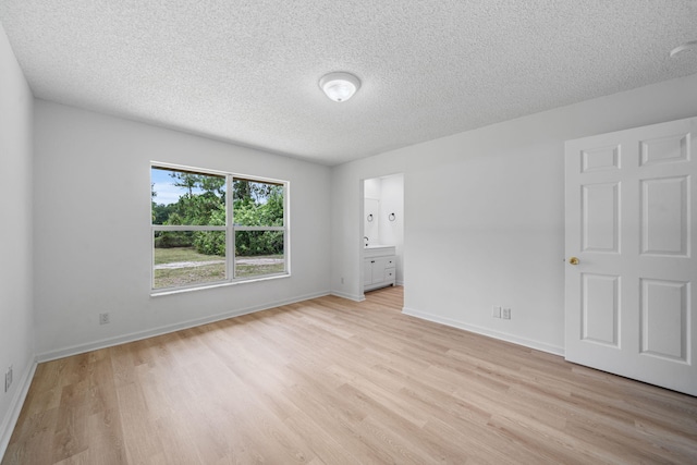 17832 43rd Rd N, Loxahatchee, FL 33470 - unfurnished bedroom featuring light wood-style flooring, a textured ceiling, baseboards, and connected bathroom