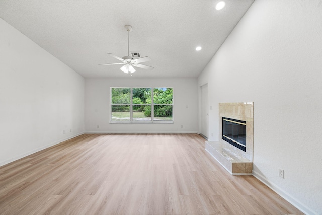 17832 43rd Rd N, Loxahatchee, FL 33470 - unfurnished living room featuring ceiling fan, light wood-style flooring, a tile fireplace, a textured ceiling, and baseboards