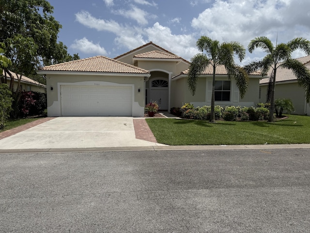 9360 Cove Point Cir, Boynton Beach, FL 33472 - mediterranean / spanish-style house featuring an attached garage, stucco siding, concrete driveway, a front lawn, and a tiled roof