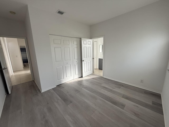 9360 Cove Point Cir, Boynton Beach, FL 33472 - unfurnished bedroom with wood finished floors, a closet, and ensuite bath