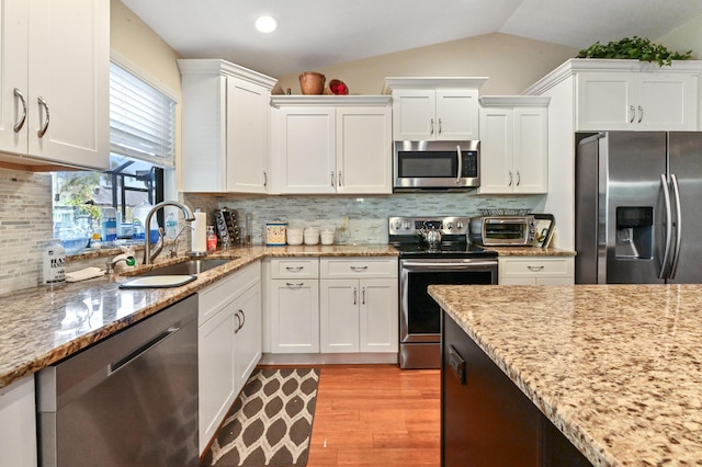 2850 NW 15th St, Delray Beach, FL 33445 - kitchen with stainless steel appliances, a sink, white cabinetry, light wood-style flooring, and lofted ceiling