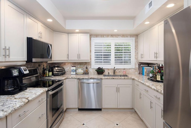 157 Capri D, Delray Beach, FL 33484 - kitchen featuring stainless steel appliances, tasteful backsplash, light tile patterned flooring, white cabinets, and recessed lighting