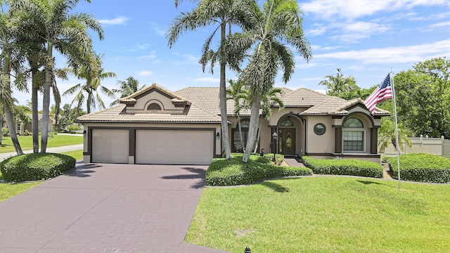 3429 SW Catskill Dr, Port Saint Lucie, FL 34953 - mediterranean / spanish house with an attached garage, concrete driveway, stucco siding, a front lawn, and a tiled roof