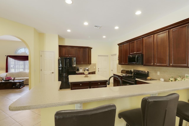 3429 SW Catskill Dr, Port Saint Lucie, FL 34953 - kitchen with black appliances, light countertops, a center island, a breakfast bar area, and tasteful backsplash