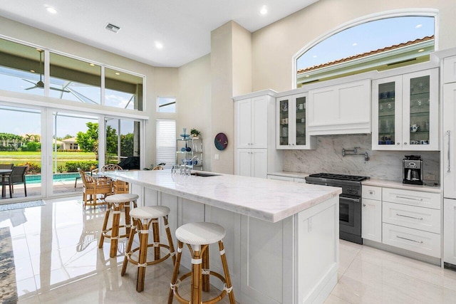 391 Isle Ct, Palm Beach Gardens, FL 33418 - kitchen featuring high end stove, healthy amount of natural light, backsplash, white cabinetry, and recessed lighting