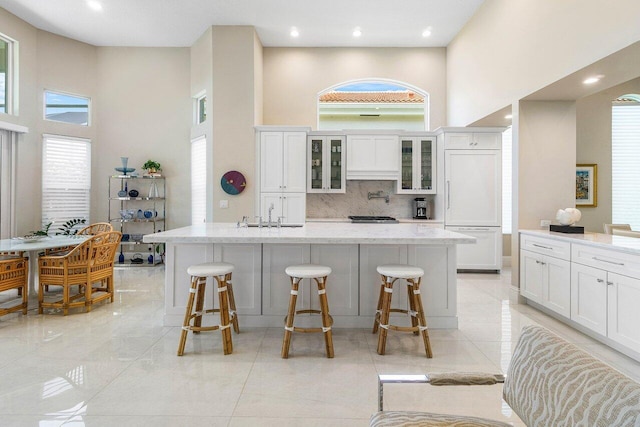 391 Isle Ct, Palm Beach Gardens, FL 33418 - kitchen with a high ceiling, a kitchen breakfast bar, white cabinetry, tasteful backsplash, and recessed lighting