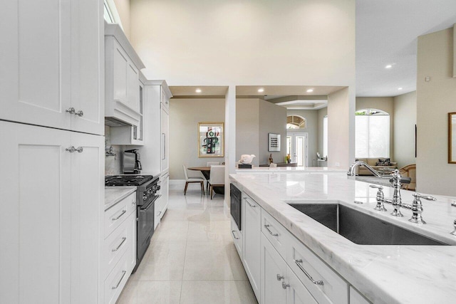 391 Isle Ct, Palm Beach Gardens, FL 33418 - kitchen with high end stove, light stone counters, recessed lighting, custom range hood, and white cabinetry