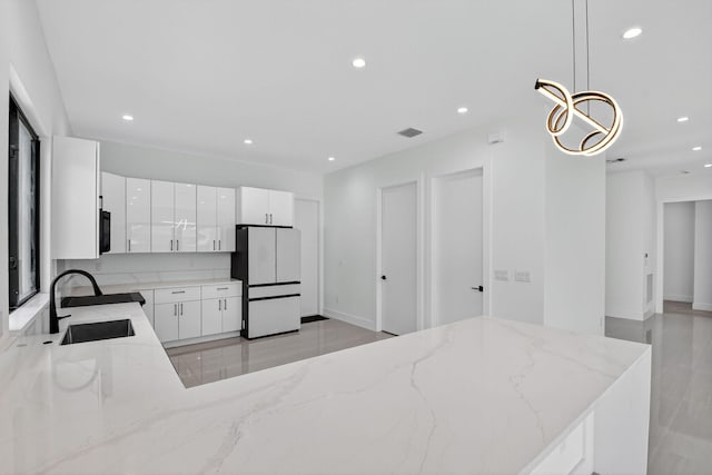 3920 Espan Ct, Palm Springs, FL 33461 - kitchen with freestanding refrigerator, recessed lighting, light stone countertops, white cabinets, and hanging light fixtures