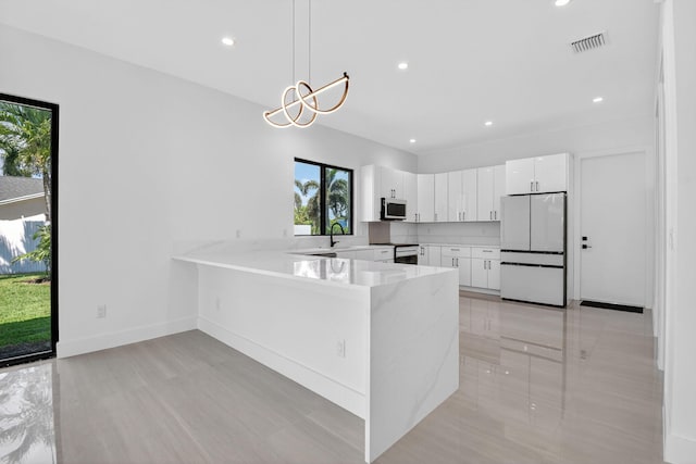 3920 Espan Ct, Palm Springs, FL 33461 - kitchen with freestanding refrigerator, a peninsula, stainless steel microwave, white cabinets, and range with electric stovetop