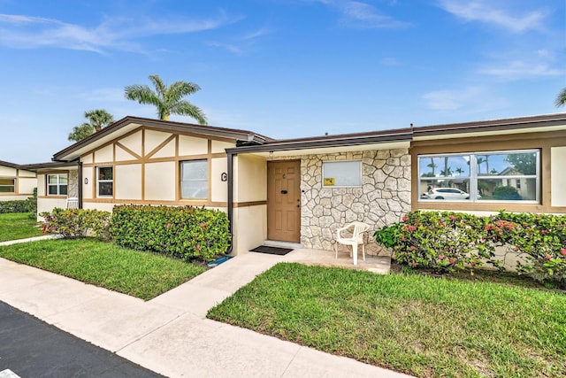 2765 Ashley Dr W Unit C, West Palm Beach, FL 33415 - view of front facade with stucco siding, a front lawn, and stone siding
