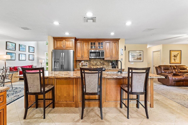 3995 Majestic Palm Way, Delray Beach, FL 33445 - kitchen featuring appliances with stainless steel finishes, open floor plan, brown cabinets, tasteful backsplash, and light stone counters